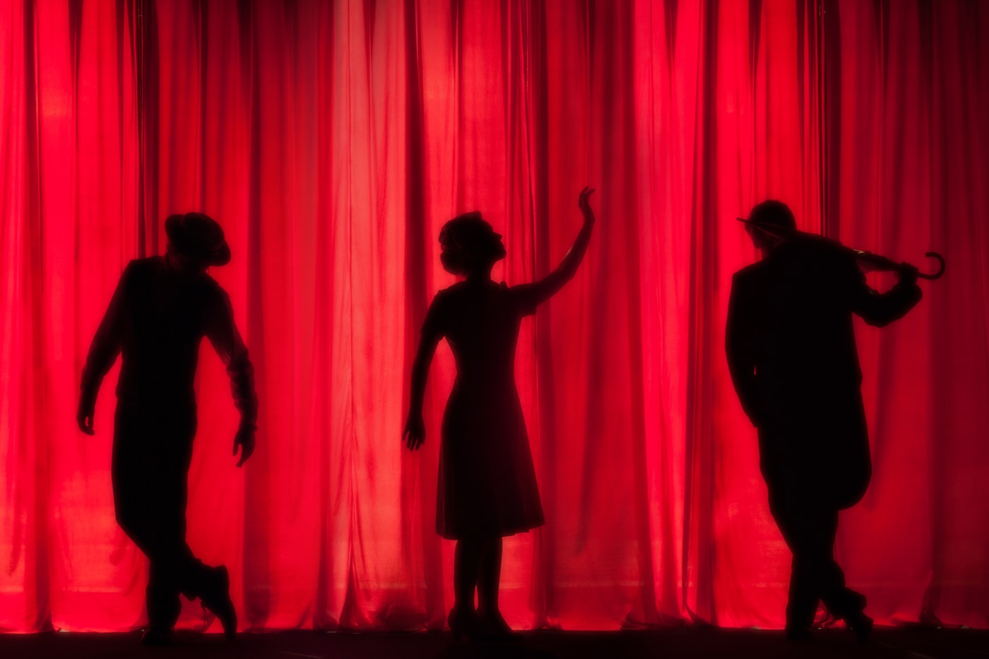 Silhouettes against a red theatre curtain